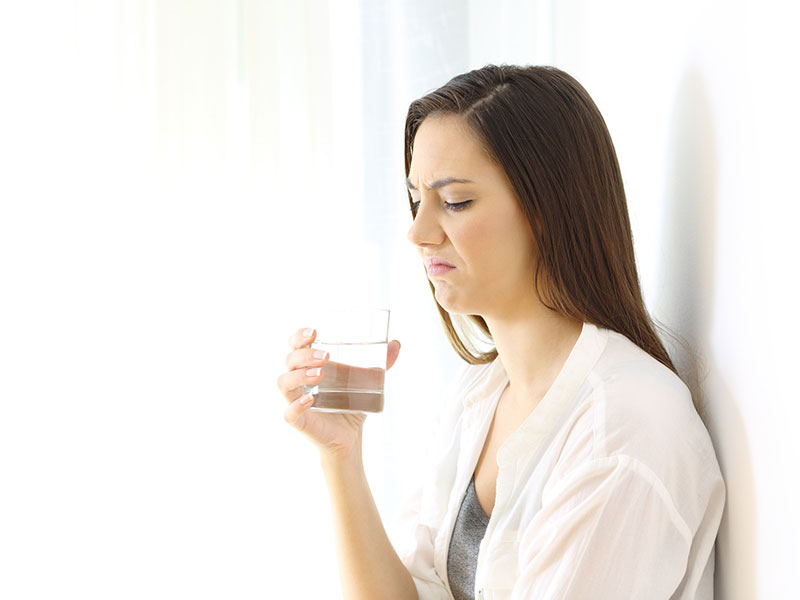 Disgusted woman drinking water with bad taste