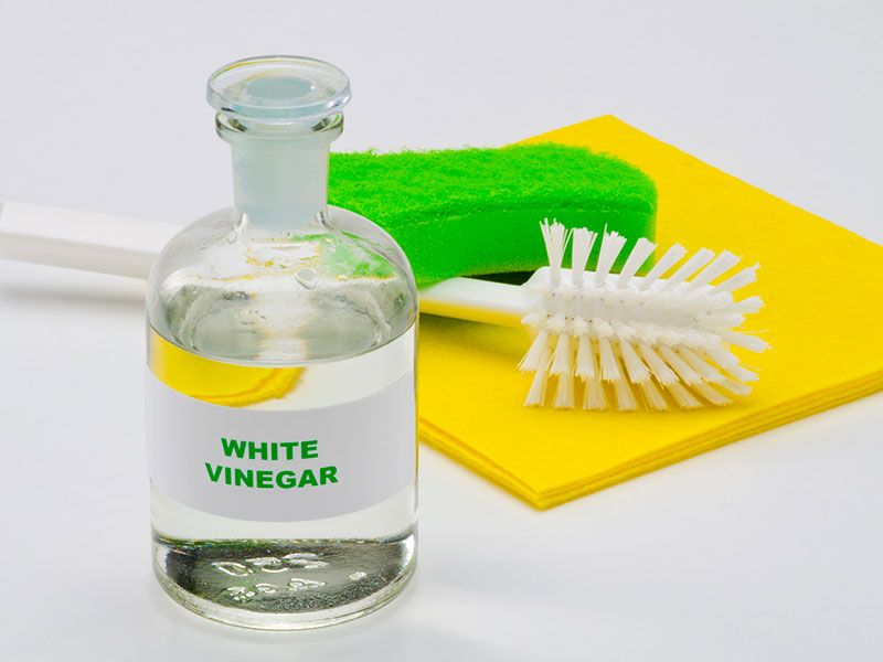 White vinegar in a glass bottle on white background