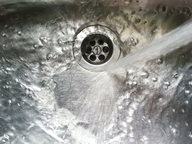 Water flows into stainless steel kitchen sink