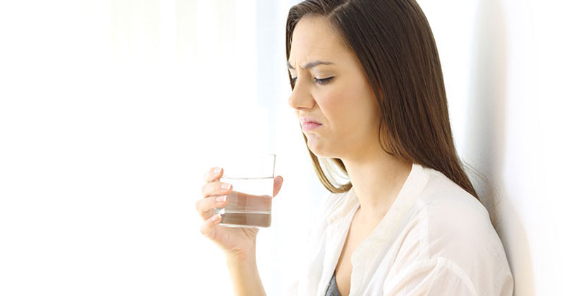 Disgusted woman drinking water with bad taste